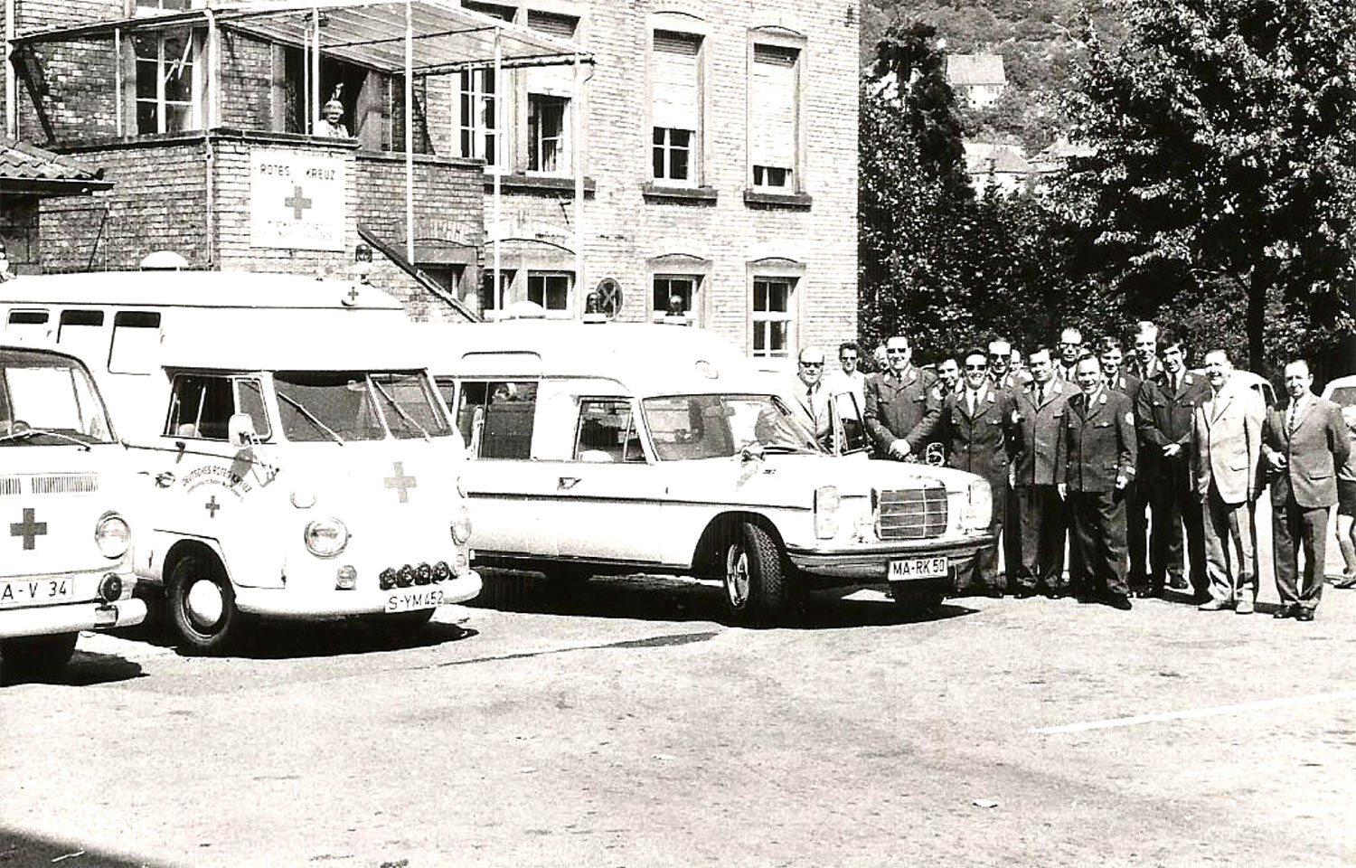 Fahrzeuge des Roten Kreuzes und eine Männergruppe.